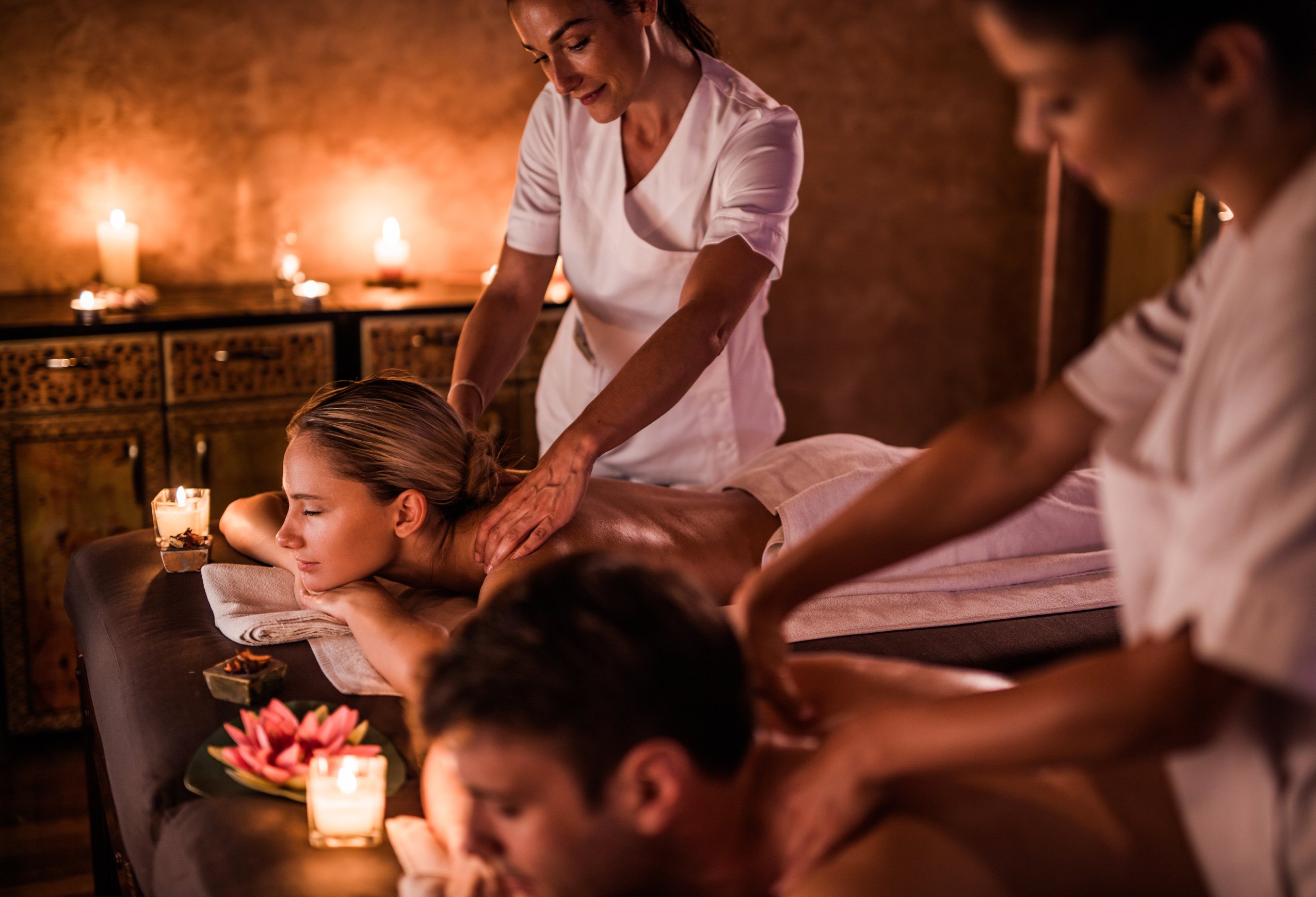 Massage therapists massaging couple during their treatment at the spa.